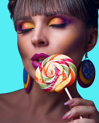 schöne junge Frau die eine bunten Lollipop lasziv an ihrem leicht geöffneten Mund hält