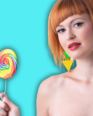 schöne junge Frau mit roten Haaren hält einen bunten Lollipop 