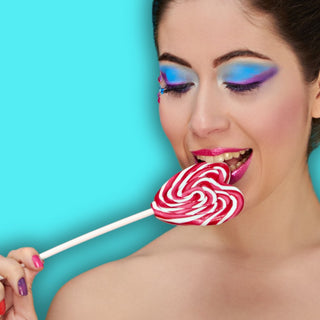 Frau ist einen Dauerlutscher Lollipop und tragt bunte Farben. Hier gelangst du zur Kategorie DRACHEN-DILDO.